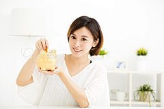 smiling young Woman Putting Coin In Piggy Bank