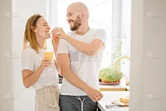 有爱心的男人给幸福的女人喂奶，关心的女人在周末一起做健康的饭菜，幸福浪漫有趣的情侣