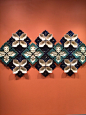 This may contain: four blue and white flower shaped plates mounted on a wall with orange walls in the background