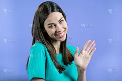 友好的女人挥手——再见，赵，再见。离别，对相机说再见。在演播室背景上挥手的漂亮女孩