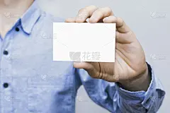 混凝土墙背景上的男子拿着白色名片。