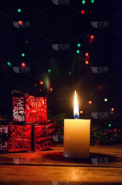 点燃的圣诞蜡烛特写背景迷你礼物，圣诞树的树枝和圣诞花环在一个木制的背景。美丽的圣诞背景，贺卡。垂直图