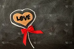 爱的情人心和红色的蝴蝶结在黑板上