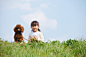 人,衣服,度假,户外,快乐_83666139_Smiling girl sitting with a cute puppy in park_创意图片_Getty Images China