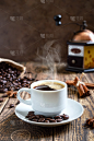 热气腾腾的咖啡放在一张旧木桌上，上面放着咖啡豆，还有手工磨咖啡机。俯视图
