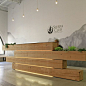 A plant-filled stack of timber beams forms the reception desk of an environmental association’s headquarters in San Francisco.