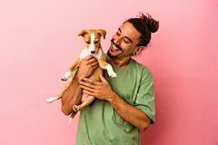 点击来源直接获取大图文件 |Young caucasian man holding his puppy isolated on pink background