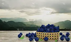 竹篮子里的蓝莓散装。深蓝色的蓝莓，清新的颜色，白色的图案落在木桌上，有山景和晨光作为壁纸或背景。水果
