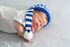 newborn in hat, asian baby stomach ache.