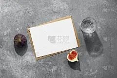 空白卡片模型，工艺信封，新鲜无花果和一杯水与长影子。灰色的具体背景。公司法人身份模板。现代简约文具静