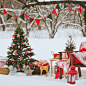 a decorated christmas tree sitting in the middle of a snow covered field next to a chair and table