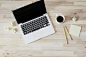 An overhead shot of a cup of coffee next to an open laptop, two pencils and a stack of sticky notes