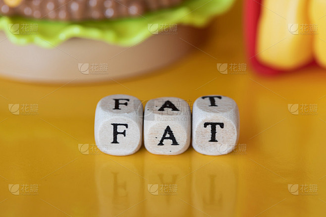 黄色背景的FAT字母。汉堡和薯条的背景。用大写字母加上正文脂肪。
