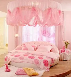 粉色帐幔 白色毛地毯 玫瑰花壁纸 粉色被套 似乎粉色已经是女生的专用颜色，用粉色作为房间的主色调，温情唯美，深浅程度不同的粉色交叉之余，更是带着一丝一缕甜蜜的情意。造型新颖的温馨圆形床，加上层叠的、轻柔的薄纱床幔，白色的毛茸茸地毯，这无疑是公主情怀的最好诠释。在床头边放置一张小茶几，铺上与床单相同款式的布料，与整个房间的格调相得益彰。桌台上摆放一束粉色鲜花，顿时整个房间气氛变得更为鲜活。另外，贴上一幅玫瑰花图案的壁纸，温情唯美公主的气息已经是无可抵挡。@北坤人素材