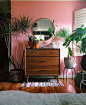 Tropisch urban jungle interieur met fel roze muur en retro ladekast.