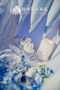 "Frozen Tale 冰雪童话“主题婚礼－怪兽花花出品 By @怪兽花花婚礼 : 整个婚礼布置采用冰蓝色、白色、银色搭配，树枝、冰山、雪地精灵等元素增添了童话乐趣和浪漫遐想。策划师把舞台打造成一个冰雪铸成的冰洞城堡，甜品区则构想成一个冰雪的童话世界，两个原创的雪地精灵围绕着一个“旋转木马式”的甜品台，桌子也设计成了矮桌，方便小朋友们自己动手拿甜品吃。