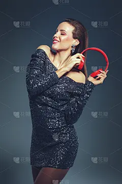 年轻的女明星拿着耳机跳舞，闭着眼睛