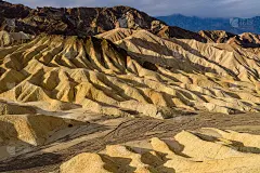 日出在泥石山丘和沟壑-一个早晨的阳光照耀在多彩的泥石山丘和沟壑在扎布里斯基点死亡谷国家公园的近距离观