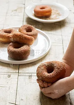 孩子们手里拿着肉桂甜甜圈，放在一张木桌上。