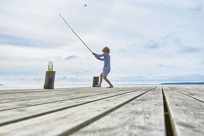 Boy fishing off lake...