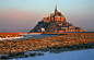 Мон-Сен-Мишель представляет собой скалистый остров, расположенный на границе Бретани и Нормандии в 400 км к северо-западу от Парижа. Это гранитная скала примерно 930 м в диаметре и высотой 92 м над уровнем моря. На ее вершине располагается монастырь и соб