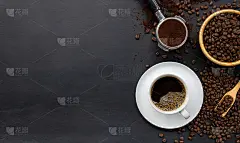 黑木桌的背景上放着一杯咖啡和豆子。俯视图