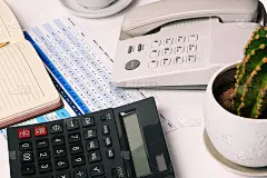 企业家的办公室有仙人掌，电话，计算器和数字统计表的办公桌。金融和会计。