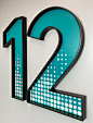 Large number signage for Chemonics International by RSM Design. Blue number "12" with white circle and black outlined signage. 