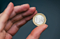 Business woman holding one euro coin between fingers