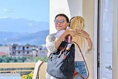 妈妈在前门附近的门廊上拥抱着十几岁的女儿，与她道别。