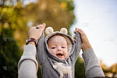 在公园里，父亲双手扶着可爱微笑的小儿子