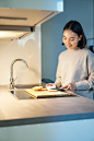Vertical shot of young asian woman cooking dinner making herself sandwitch smiling while standing on