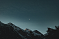 the moon is shining in the sky over the mountains