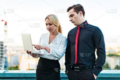几个商人，严肃的黑发男人和迷人的金发女人站在屋顶上看笔记本电脑