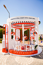 This may contain: an orange and white kiosk sitting on the side of a road