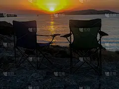 两张椅子对着大海和岛屿的日落景色
