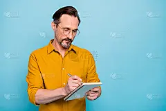 肖像严肃专注的人大学教授为他的学生准备讲座写钢笔抄写本穿现代服装孤立在蓝色背景