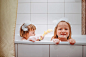 家的舒适:真正和舒适的童年场景-兄弟姐妹玩拖拉机在一个充满泡沫的浴缸。图片下载