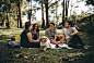 Group of People Sitting on White Mat on Grass Field