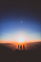 silhouette of three person standing on mountain