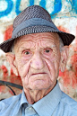 戴帽子的老人这个男人坐在阿尔巴尼亚杜雷西罗马露天剧场外面的树荫下。 挺有个性的。