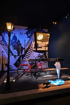 展览⎜爱马仕“奇境漫步”中的奇幻之处 : 雨后 闲情漫步有时也会遇到始料不及，比如变化多端的天气，为你带来陌生又熟悉的场景。伞上的雨珠顺势滑下，跌落在长椅旁的“水洼”里，而它倒映着雨后初晴的天空正是由艺术家Nicolas Tourte创作的数字艺术装置。...