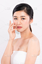 美丽的年轻亚洲女人触摸她的干净的脸与新鲜健康的皮肤，隔离在白色的背景，美容化妆品和面部治疗概念，