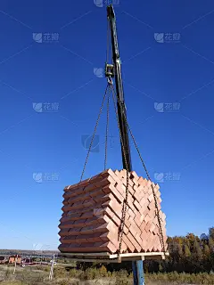 汽车起重机在秋天蓝色天空的背景下装载并卸下砖块