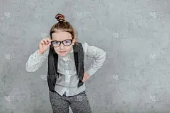 一个小商人女士的特写在一个灰色的背景。穿着眼镜。握着他们的手就是一根商业魔杖。我要去看摄像机。