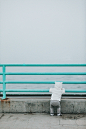 toddler standing while resting arm on rail facing body of water