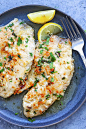 Parmesan baked tilapia fish with fresh lemon, ready to be served.