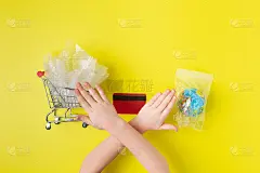 小女孩用手展示阻止塑料污染。一次性塑料购物车。用塑料包装的地球