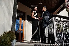 可爱的印度夫妇在爱，穿着纱丽和优雅的西装，摆姿势的室外阳台在夏天阳光灿烂的一天。