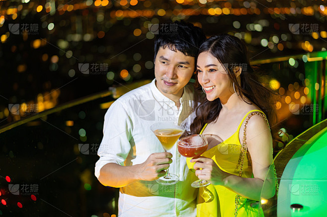 夫妇在夜总会与鸡尾酒在夜晚的城市背景